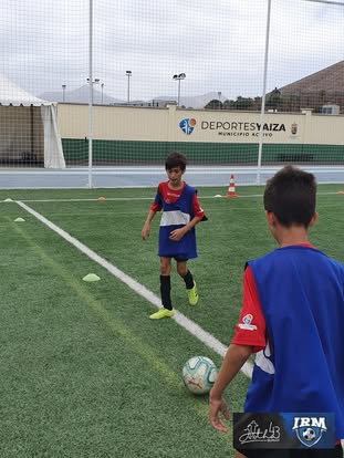Dos jóvenes futbolistas realizando un ejercicio técnico de pase y toma de decisión