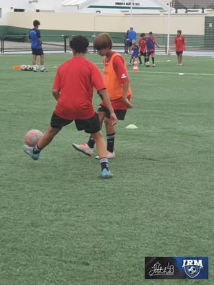 Futbolistas jóvenes practicando conducción y duelo con balón en un entrenamiento de IRM