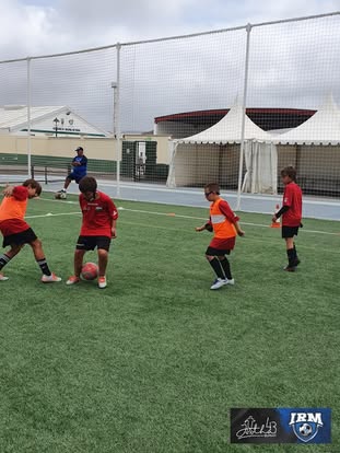 Grupo de jóvenes futbolistas realizando un ejercicio de juego reducido en un campus de IRM